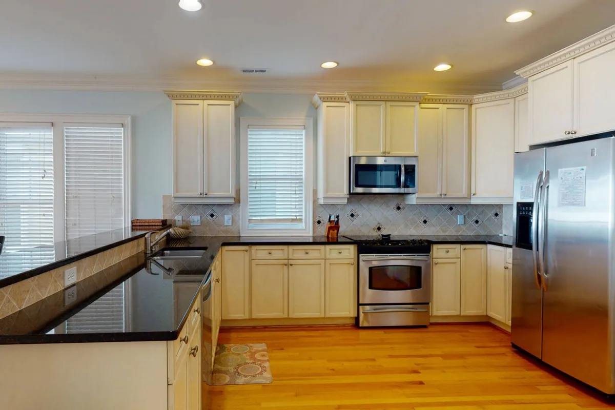A stylish, well-equipped kitchen with a granite-topped island, stainless steel appliances, and a window allowing in natural light. The scene is both practical and inviting, hinting at the culinary possibilities for group meals, casual brunches, or family-style feasts.