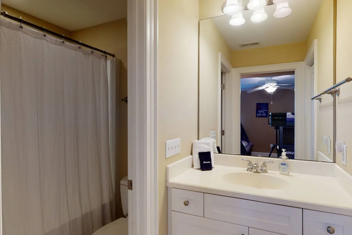 A bright and inviting bathroom displaying a vanity with a sink, a mirror, neatly hung towels, and a stylish shower curtain. The atmosphere is fresh and practical, emphasizing daily comfort.