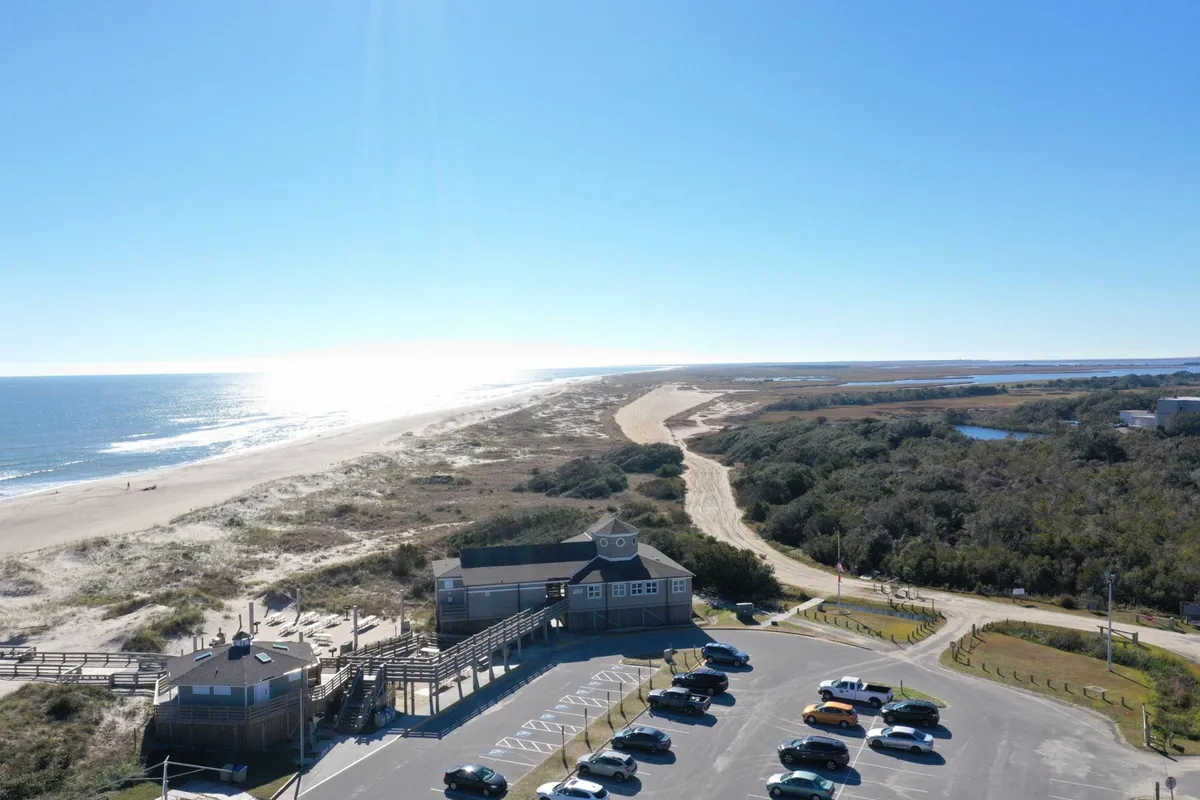 A panoramic view of the beach, ocean, boardwalk, and surrounding vegetation, with ample open space ideal for walking, picnicking, or simply soaking up the scenery. The relaxed mood and variety of natural features make it welcoming for both people and their pets.