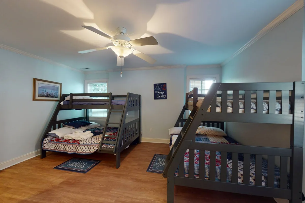 A cheerful bunk room designed for kids, with sturdy bunk beds, playful wall art, and a ceiling fan for comfort. The space is bright and inviting, making it ideal for late-night chats and playful moments before bed.
